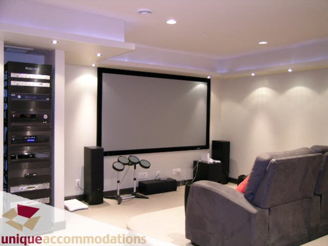 Living room with a large projector screen, modern furniture, and entertainment setup. - 2429 West 19th Avenue, Vancouver West Side