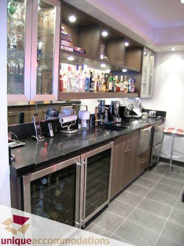 Bright kitchen with granite countertops and stainless steel appliances, showcasing a well-stocked bar area.