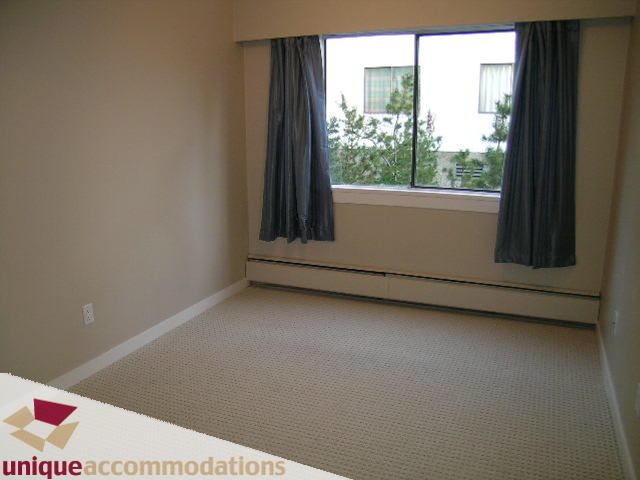 Bright bedroom with large windows and neutral carpeting. - 110 - 225 West 3rd Street, North Vancouver