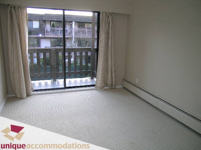 Bright bedroom with large window, city view, and neutral decor. - 110 - 225 West 3rd Street, North Vancouver