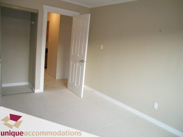 Bright bedroom with white door and closet, neutral walls and carpeted floor. - 110 - 225 West 3rd Street, North Vancouver