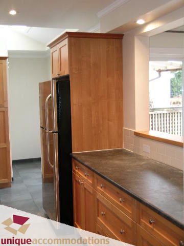 Bright kitchen with wooden cabinets, granite countertops, and a city view. - 1773 Rufus Drive, North Vancouver