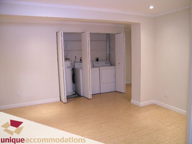 Furnished living room with hardwood floors and a built-in laundry area. - 1773 Rufus Drive, North Vancouver