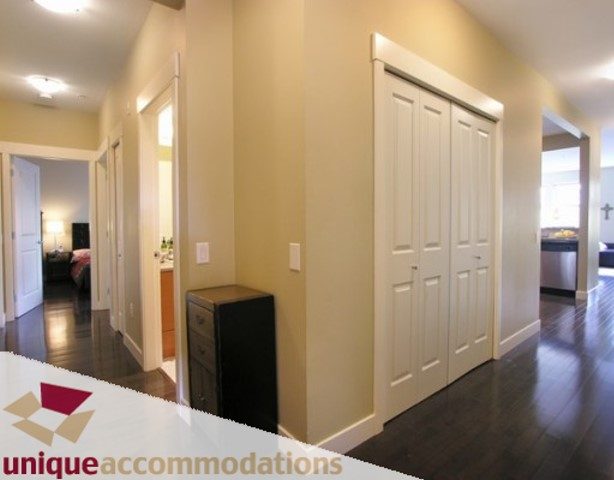 Furnished hallway with hardwood floors and white doors leading to bedrooms. - 107 - 188 West 29th Street, North Vancouver