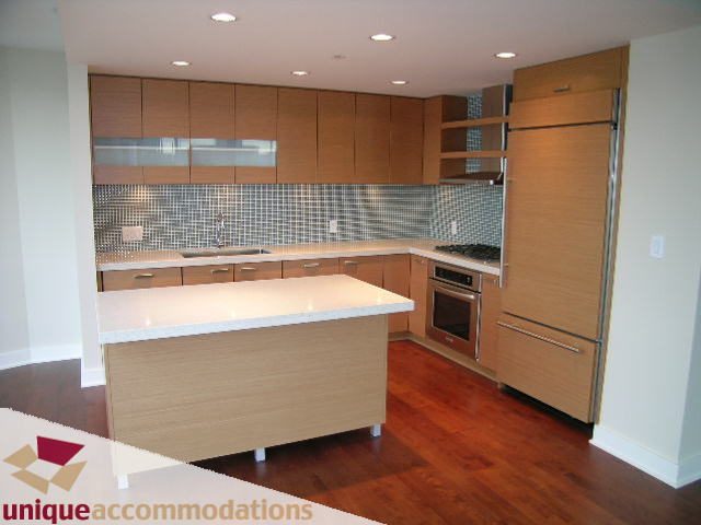 Modern kitchen with light wood cabinets, white countertops, and hardwood floors. - 2401-1277 Melville, Vancouver Downtown
