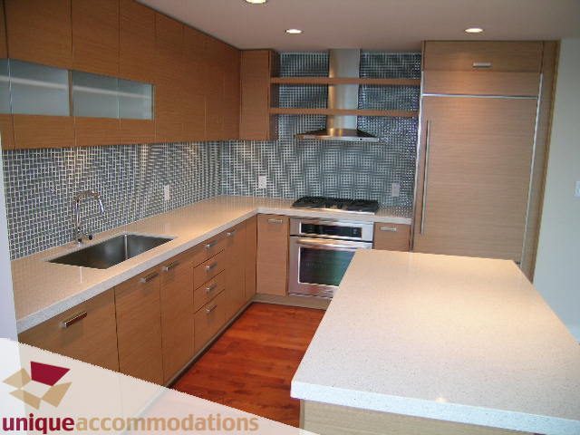 Modern kitchen with sleek countertops, hardwood floors, and a tiled backsplash. - 2401-1277 Melville, Vancouver Downtown