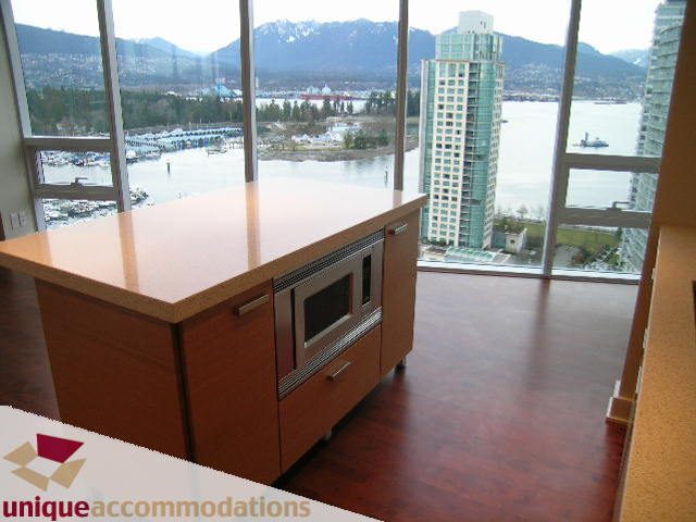 Spacious kitchen with wooden countertops and hardwood floors, featuring a stunning city view. - 2401-1277 Melville, Vancouver Downtown