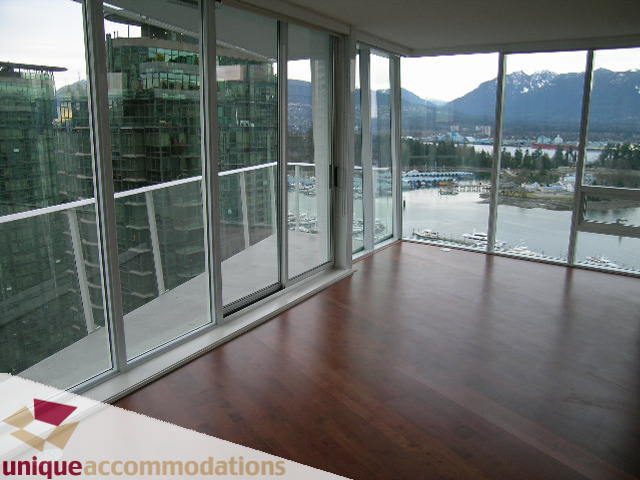 Spacious living room with hardwood floors, large windows, and a stunning city view. - 2401-1277 Melville, Vancouver Downtown