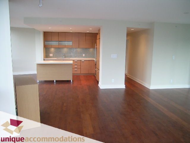 Spacious open-concept living area with hardwood floors and a modern kitchen featuring granite countertops and a tiled...