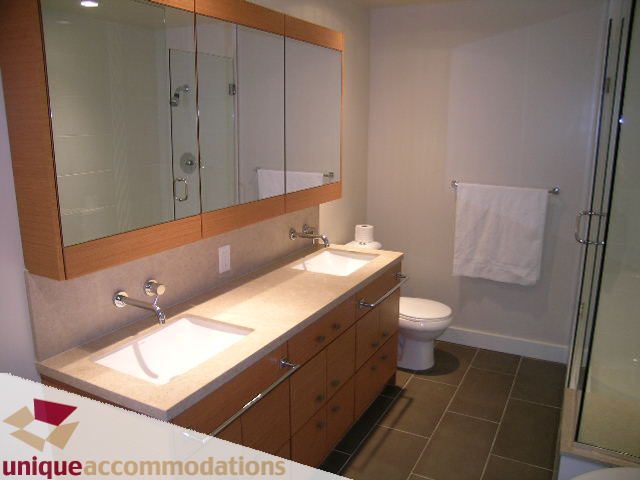 Spacious bathroom with modern vanity, glass shower, and sleek countertop. - 2401-1277 Melville, Vancouver Downtown