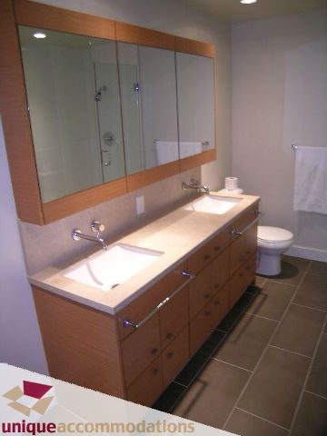 Modern bathroom with light wood cabinets and a large mirror, featuring a sleek countertop and a stylish sink. - 2401-1277 Melville, Vancouver Downtown