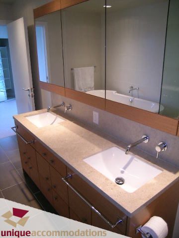 Spacious bathroom with dual sinks, wooden cabinets, and a large mirror. - 2401-1277 Melville, Vancouver Downtown