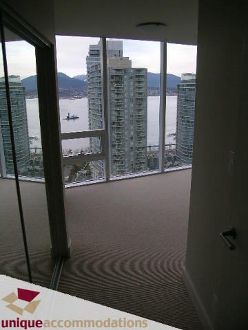 Spacious living room with a stunning city view and modern furnishings. - 2401-1277 Melville, Vancouver Downtown