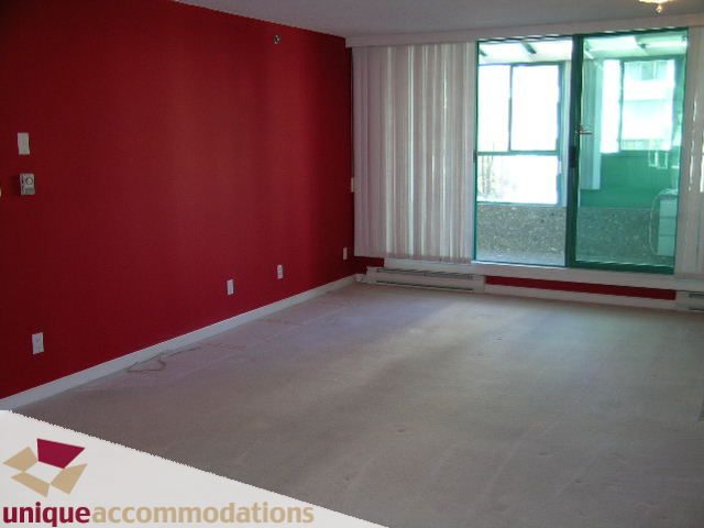 Bright living room with red accent wall and sliding glass door leading to balcony. - 703 - 1132 Haro Street, Vancouver Downtown