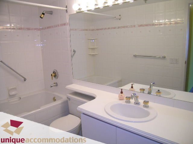 Furnished bathroom with white countertop and sink, modern fixtures, and a large mirror. - 703 - 1132 Haro Street, Vancouver Downtown