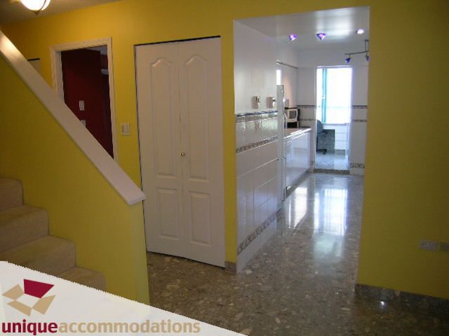 Bright kitchen with white cabinets, marble countertops, and a view of the living area. - 703 - 1132 Haro Street, Vancouver Downtown