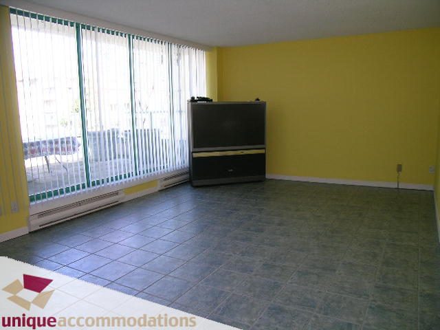 Bright living room with tiled floors, large windows, and a flat-screen TV. - 703 - 1132 Haro Street, Vancouver Downtown