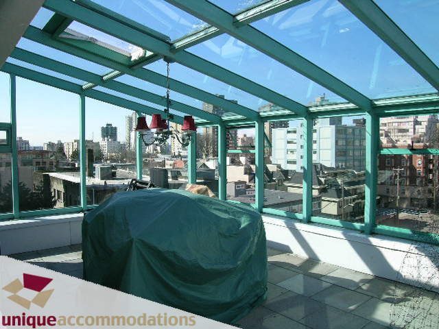 Bright rooftop patio with glass ceiling, city view, and covered furniture. - 703 - 1132 Haro Street, Vancouver Downtown