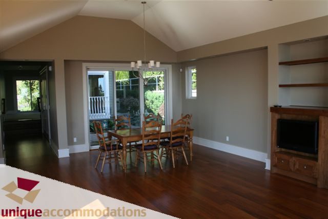 Spacious dining area with hardwood floors and large windows, leading to a balcony. - 2550 Marr Creek Ct, West Vancouver