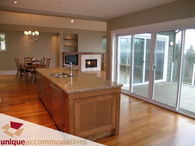 Open kitchen with granite countertops, hardwood floors, and sliding glass doors leading to a patio. - 2550 Marr Creek Ct, West Vancouver