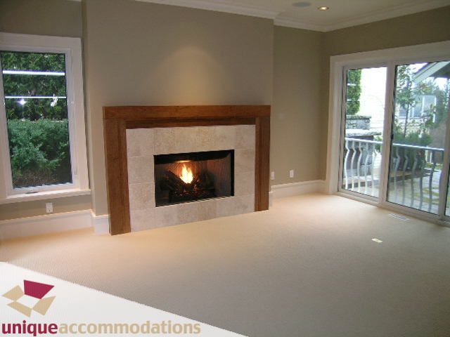 Spacious living room with fireplace, sliding glass doors to patio, neutral tones. - 2550 Marr Creek Ct, West Vancouver