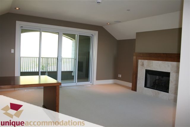 Spacious living room with modern fireplace and large sliding glass doors leading to a balcony. - 2550 Marr Creek Ct, West Vancouver