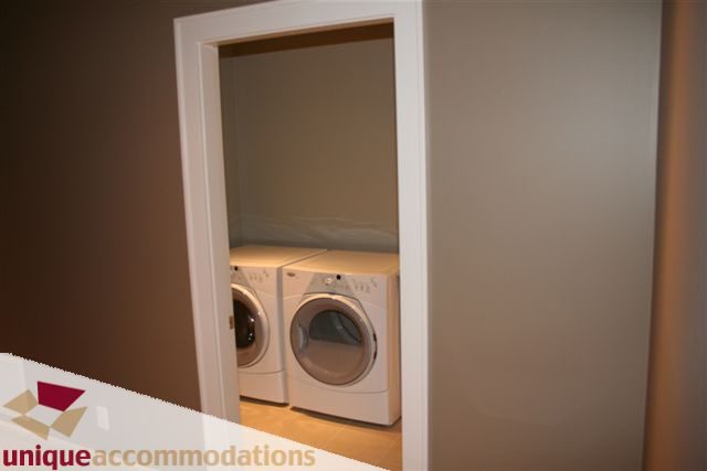 Laundry room with stacked washer and dryer, neutral walls. - 2550 Marr Creek Ct, West Vancouver