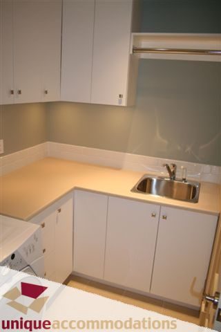 Bright kitchen with white cabinets, light countertops, and stainless steel sink. - 2550 Marr Creek Ct, West Vancouver