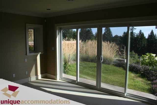 Spacious living room with sliding glass doors leading to a serene garden view. - 2550 Marr Creek Ct, West Vancouver