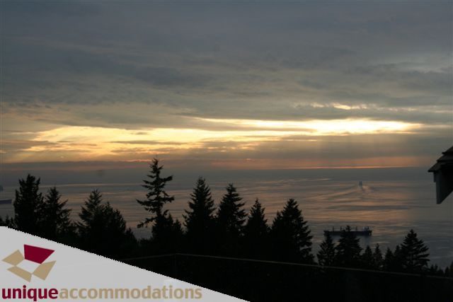 Furnished living room with a stunning ocean view at sunset. - 2550 Marr Creek Ct, West Vancouver