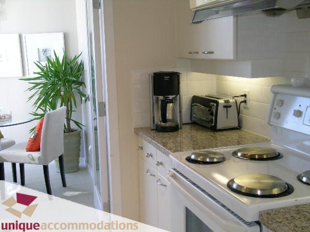 Bright kitchen with granite countertops, modern appliances, and a cozy dining nook featuring a potted plant.