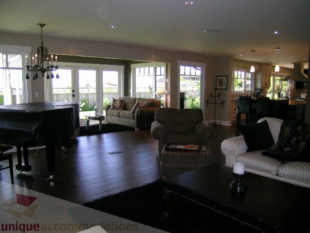 Spacious living room with hardwood floors, large windows, and a grand piano. - 4221 Rockridge Crescent, West Vancouver