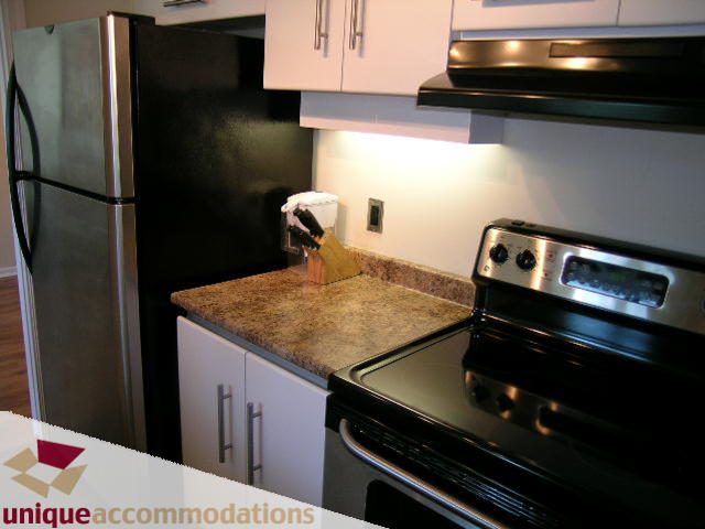 Bright kitchen with granite countertops, stainless steel appliances, and black backsplash. - 2005 - 1238 Melville, Vancouver Downtown
