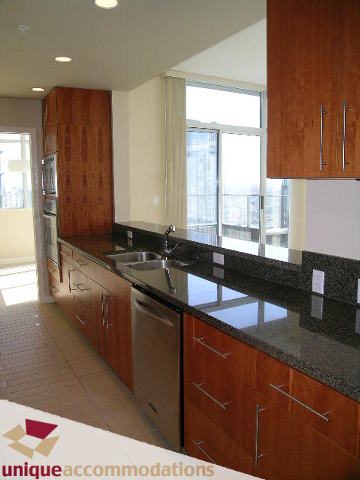 Bright kitchen with modern black countertops, hardwood floors, and a city view. - 3602 - 583 Beach Crescent, Vancouver Downtown