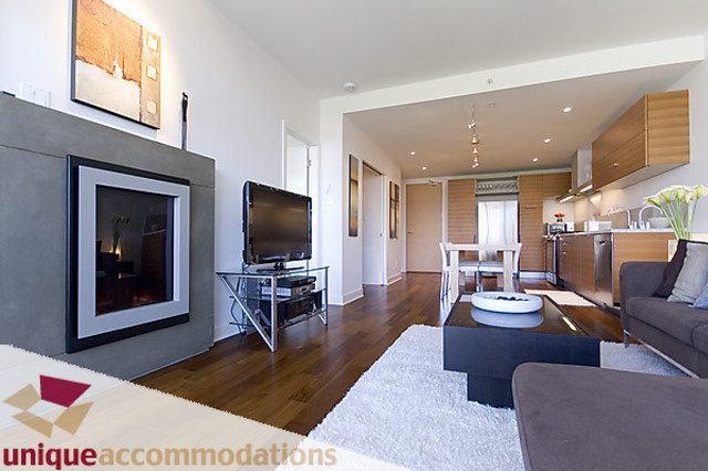 Furnished living room with hardwood floors, modern fireplace, and open kitchen in the background. - 505 - 1808 West 1st Avenue, Vancouver West Side