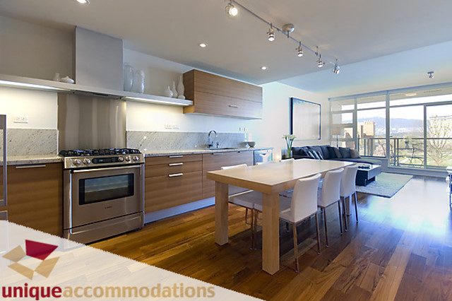 Furnished 1-bedroom + den with hardwood floors, city view, and modern kitchen with granite countertops.