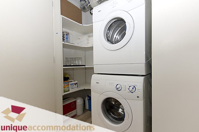 Bright laundry room with stacked washer and dryer, white cabinets, and modern appliances. - 505 - 1808 West 1st Avenue, Vancouver West Side