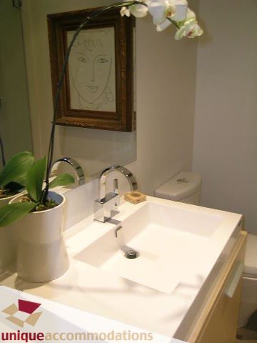 Bright bathroom with white countertops and a framed portrait above the toilet. - 307- 1808 West 1st Avenue, Vancouver West Side