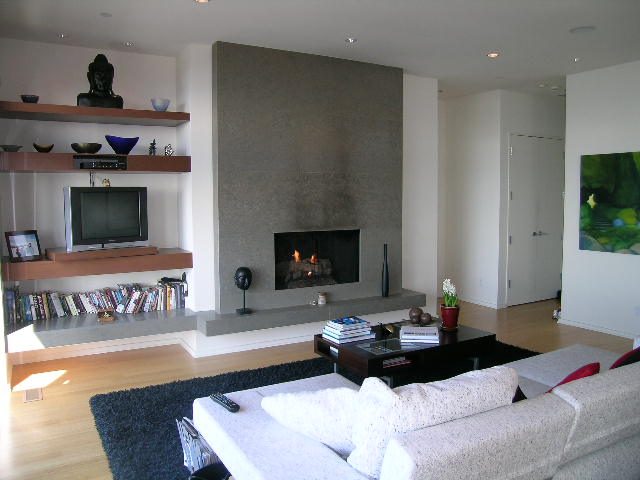 Modern living room with concrete fireplace, hardwood floors, and a cozy sofa. - 2456 Hudson Court, West Vancouver
