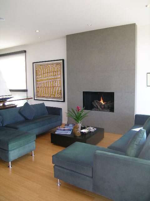 Modern living room with a fireplace, teal sofas, and a large abstract painting. - 2456 Hudson Court, West Vancouver