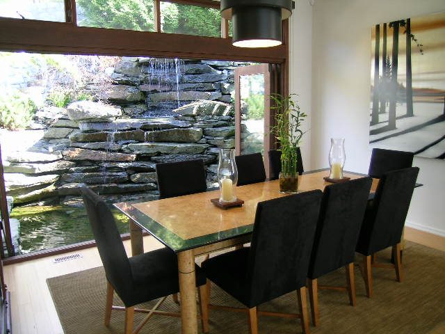 Dining room with stone waterfall view, modern decor, and black chairs. - 2456 Hudson Court, West Vancouver