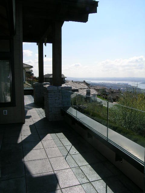 Balcony with glass railings, city view, and stone flooring. - 2456 Hudson Court, West Vancouver