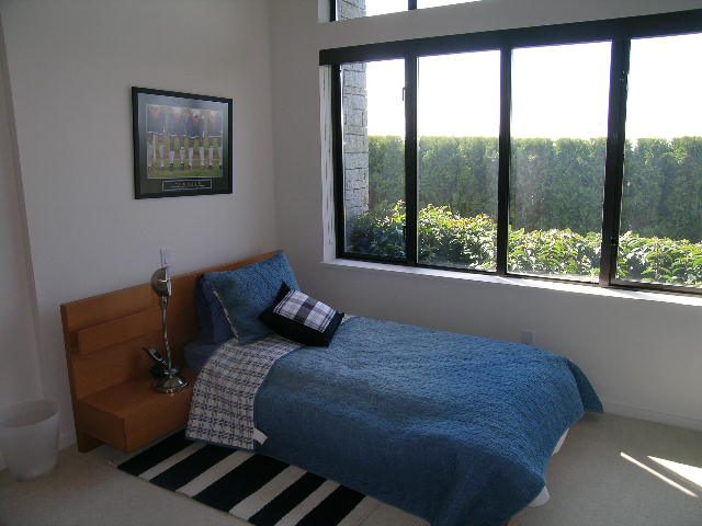 Bright bedroom with large windows, blue bedding, and a framed sports print on the wall. - 2456 Hudson Court, West Vancouver