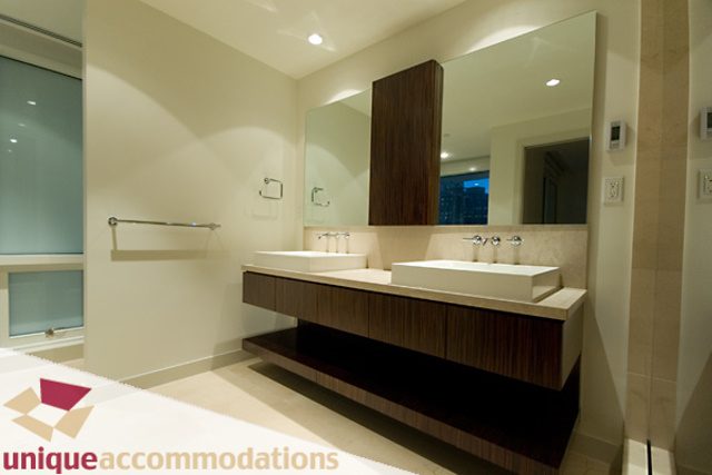 Modern bathroom with sleek countertop and large mirror, showcasing a city view. - 903 - 1139 West Cordova Street, Vancouver Downtown