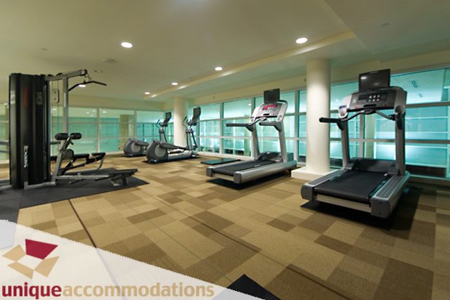 Bright and spacious fitness room with treadmills and weight machines, large windows offering city views.