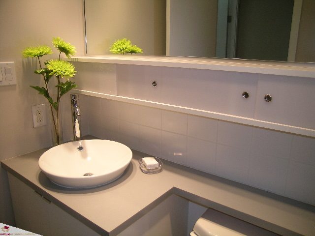 Bright bathroom with modern sink, white cabinetry, and a vase of green flowers. - 902 - 928 Beatty Street, Vancouver Downtown