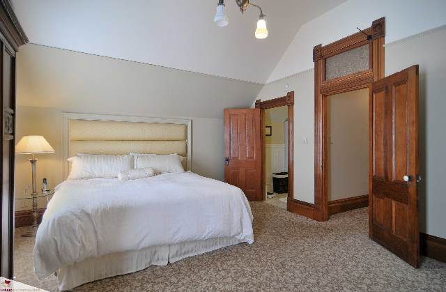 Spacious bedroom with wooden headboard and large mirror, featuring a cozy bed setup. - 1150 Haro Street, Vancouver Downtown