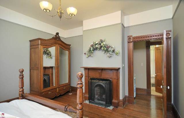 Bright bedroom with wooden furniture, floral decor, and a large mirror. - 1150 Haro Street, Vancouver Downtown