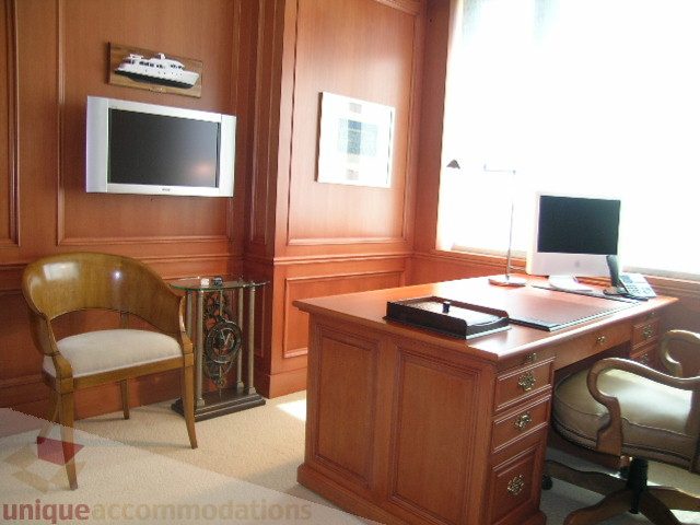 Furnished office with wooden desk, chair, and TV mounted on wall. - 802 - 323 Jervis Street, Vancouver Downtown