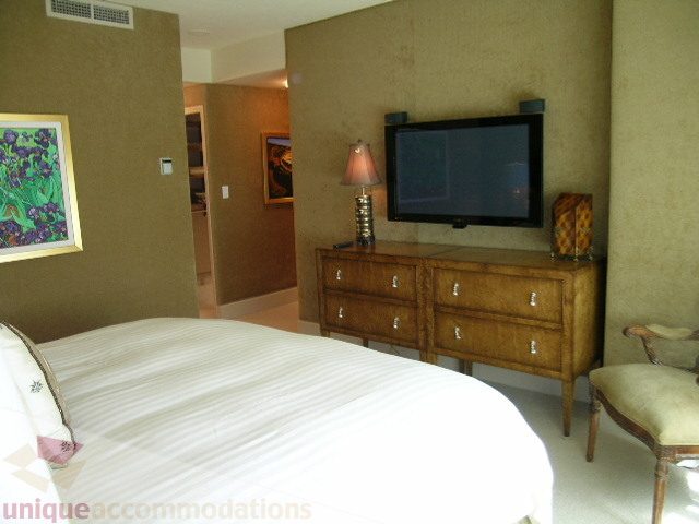 Furnished bedroom with wooden furniture, flat-screen TV, and artwork on the wall. - 802 - 323 Jervis Street, Vancouver Downtown